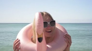 Deniz sahilinde şişme yüzüklü komik bir kadın.