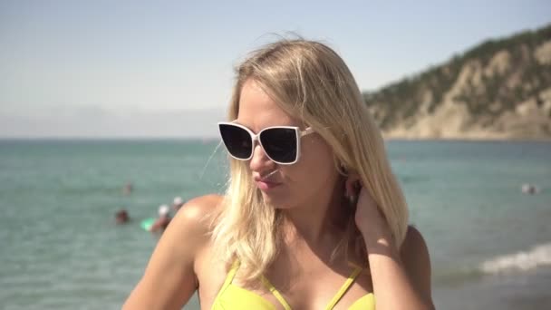 Displeased young woman on the beach. Capricious sad woman on the background of the sea — Stock Video