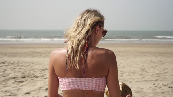 Красива жінка п'є молоко зі свіжого кокоса на тропічному пляжі на тлі моря — стокове відео