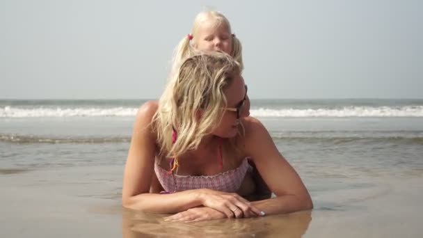 Mutlu aile, kızıyla birlikte kumlu deniz kıyısında uzanan bir kadın. — Stok video