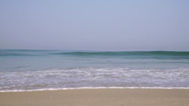 Okyanus, boş kumlu sahil. Deniz dalgaları ve köpük, yavaş çekim. Güzel doğal deniz arka planı