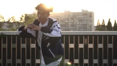 Genç adam arka planda hip-hop ve break dans yapıyor, ağır çekim.