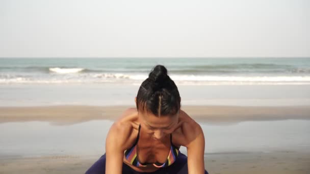 Aziatisch oosterse vrouw praktijken yoga op de achtergrond van de zee — Stockvideo