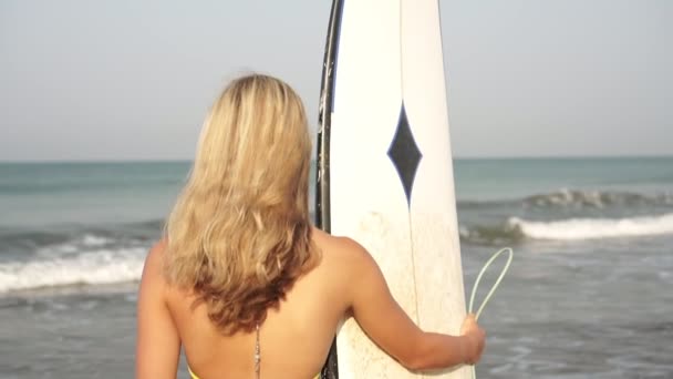 魅力的な若いです女性サーファーとともにサーフボード見ますザ海 — ストック動画
