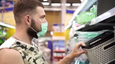 Erkek alışverişçi yüzünde tıbbi koruyucu maske takıyor.