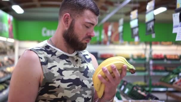 Komoly, erős, szakállas férfi banánt szed a boltban. — Stock videók