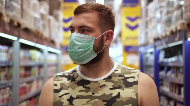 Mann mit medizinischer Maske im Geschäft. Coronavirus-Präventionskonzept. Ein Mann in einem Supermarkt mit einer antiviralen Maske — Stockvideo