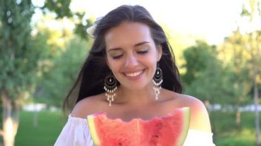 Doğada olgun kırmızı karpuz yiyen güzel genç bir kadın.