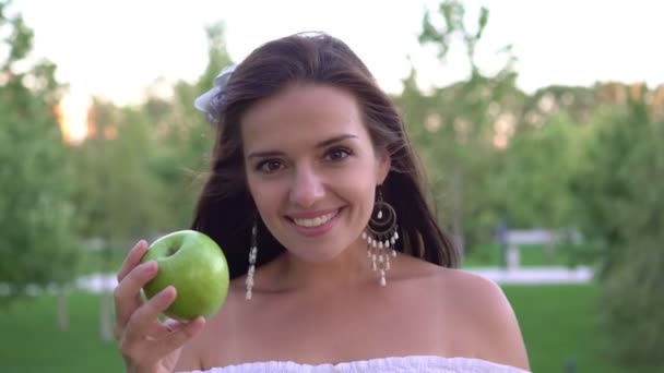 Привлекательная молодая женщина ест зеленое яблоко на открытом воздухе — стоковое видео