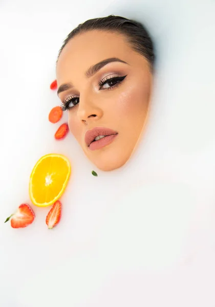 güzel model kadın yüz meyve portakal ve çilek ile süt banyo güzellik bakımı ve Spa kavramı yakın yukarı makyaj 