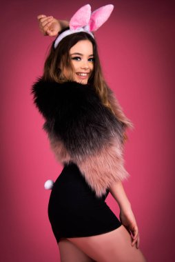 Tavşan partisi kostümü giyen sevimli bir kız, arka planda izole edilmiş, pembe sahte kürk moda moda parti tarzı.