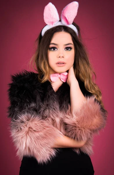 Tavşan partisi kostümü giyen sevimli bir kız, arka planda izole edilmiş, pembe sahte kürk moda moda parti tarzı.