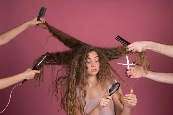 Hair dresser concept, beautiful young woman with long curly hair, hands around head, holding scissors, comb, iron, magnifier