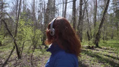 Genç bir kız, öğleden sonra parkta yürüyor. Kulaklık üzerinden müzik kız. Sağlıklı yaşam tarzı.