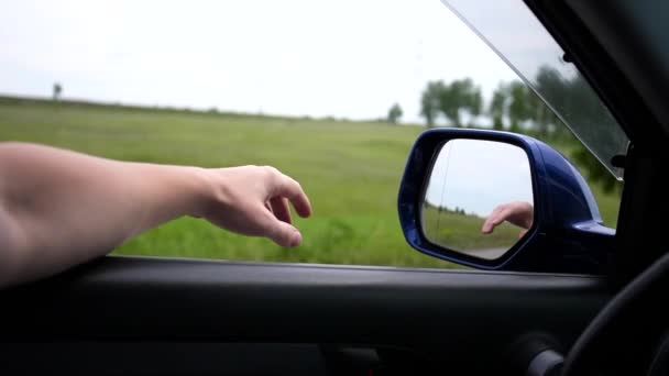 Förflyttning av bilen på motorvägen. Föraren kör med fönstret öppet. Speglar händer i spegeln. familj resa — Stockvideo