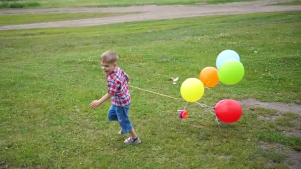 幸せな小さな赤ちゃんは、風船で走り回って楽しい。屋外のレクリエーション。お祝いや楽しい。子供の誕生日 — ストック動画