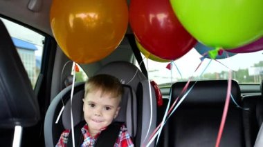 Mutlu bir çocuk bir arabaya binme. Şenlikli ruh hali, gülümseme, kahkaha. Balonlar arabada. Childs'ın Doğum günü