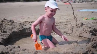 Sahilde kum ile oynayan çocuk. Yaz güneşli bir gün, iyi bir ruh hali.
