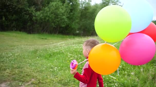 Pequeño bebé feliz, divertido corriendo con globos. Recreo al aire libre. Celebración y divertido.Cumpleaños de niños — Vídeo de stock