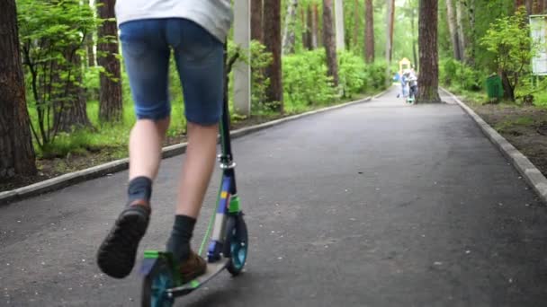 O tipo monta uma scooter no Parque no início da Primavera. Derretendo neve, neve e poças no asfalto. Esportes ao ar livre. Fechar. — Vídeo de Stock