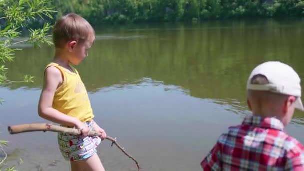 2 人の子供は、川の銀行の釣竿で魚を捕まえます。美しい夏の風景です。屋外レクリエーション. — ストック動画