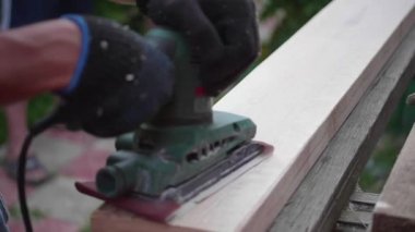 Adam-Builder, elektrikli el aletleri ile bir tezgah üzerinde çalışıyor. Tahtadan yapılmış nesneleri inşaatı. Bir araç ile ahşap kurulların işleme
