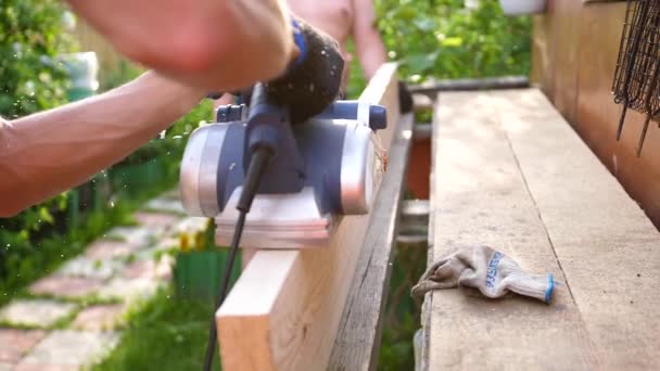 Man-Builder, werken aan een werkbank met elektrisch gereedschap. Bouw van objecten van hout gemaakt. Verwerking van houten planken met een gereedschap — Stockvideo