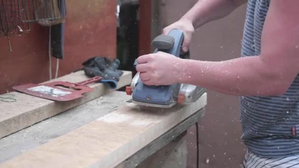 Construcción de objetos de madera. Procesamiento de tablas de madera con una herramienta. Man-Builder, trabajando en un banco de trabajo con herramientas eléctricas . — Vídeos de Stock