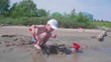 Sahilde kum ile oynayan çocuk. Yaz güneşli bir gün, iyi bir ruh hali.