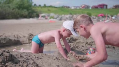 bir çocukla kumsalda oynarken ağabeyi. Kum kalıpları yapmak için