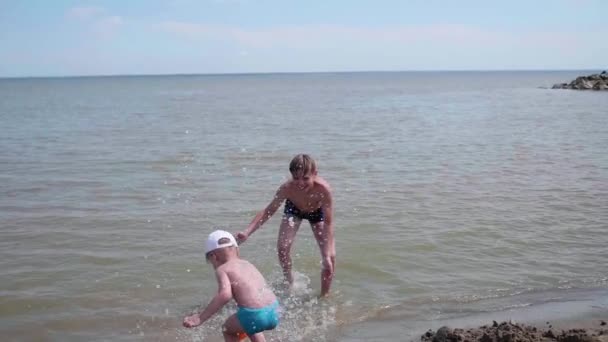 Kinderen spelen op zee, het maken van een plons water. Entertainment en openluchtspelen. — Stockvideo