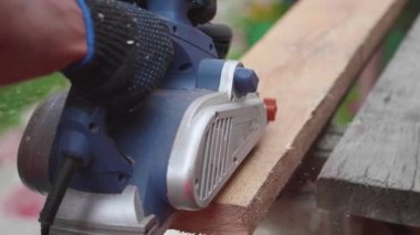 Adam-Builder, elektrikli el aletleri ile bir tezgah üzerinde çalışıyor. Tahtadan yapılmış nesneleri inşaatı. Bir araç ile ahşap kurulların işleme