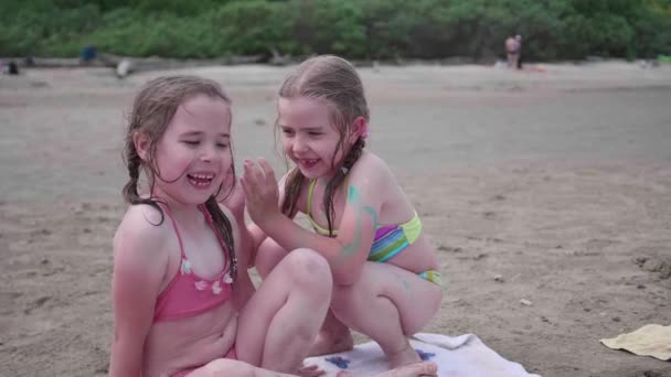 Дві сестри дівчата грають на пляжі. Сімейний відпочинок біля моря — стокове відео