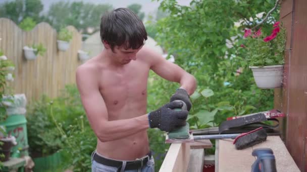 Man-Builder, werken aan een werkbank met elektrisch gereedschap. Bouw van objecten van hout gemaakt. Verwerking van houten planken met een gereedschap — Stockvideo