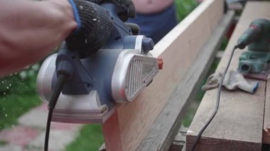 Adam-Builder, elektrikli el aletleri ile bir tezgah üzerinde çalışıyor. Tahtadan yapılmış nesneleri inşaatı. Bir araç ile ahşap kurulların işleme