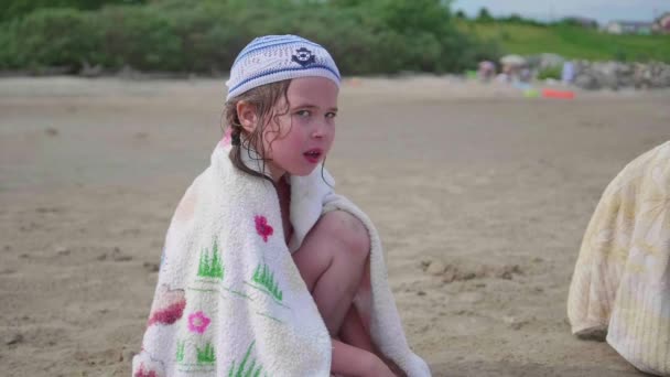 Liten flicka sitter på stranden, varm sommardag. — Stockvideo