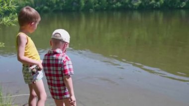 İki çocuk nehir banka balıkçılık çubuklar ile balık yakalamak. Güzel yaz manzara. Açık rekreasyon.