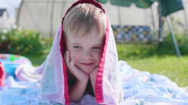 Sıcak yaz gününde çim üzerinde yalan küçük bir çocuk. Çocuk eğlence ve boş zaman geçirmek için etkin. Mutlu çocukluk