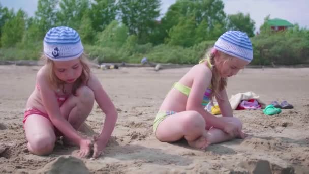 Zwei Mädchen spielen am Strand und basteln Sandfiguren. Heißer Sommertag. Familienurlaub am Meer