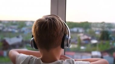 Genç adam penceresi açılır. Arka plan bulanık teen zevk müzik kulaklık.