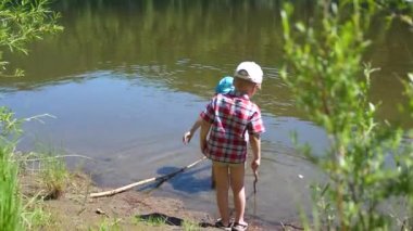 İki çocuk nehir banka balıkçılık çubuklar ile balık yakalamak. Güzel yaz manzara. Açık rekreasyon.