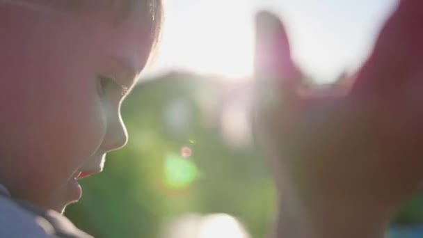 Uma pequena caneta infantil acenando para o sol. Os raios passam pelos teus dedos. Bem-vindo ao sol — Vídeo de Stock