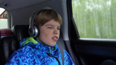 Aile gezisi. Aile karayolu üzerinde kullanıyor. Teen arabada oturan ve kulaklık üzerinden müzik