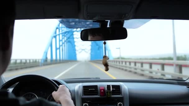 Voyage en famille en voiture. Il y a un peu de pluie, la voiture passe sur le pont sur la rivière — Video