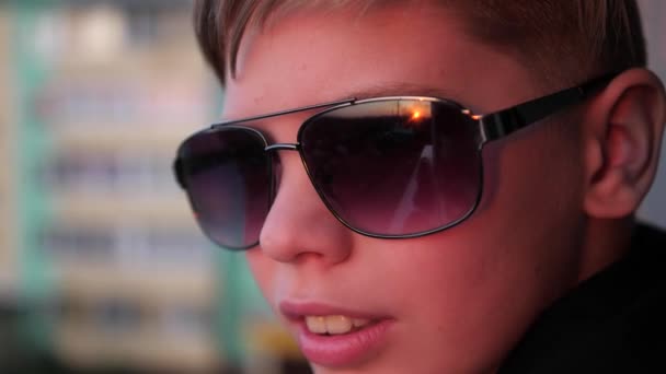 Der Typ mit der Sonnenbrille beobachtet den Sonnenuntergang. die sonnenstrahlen spiegeln sich im glas — Stockvideo