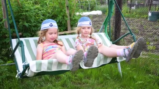 Two girls sisters swing on a swing. Entertainment and outdoor recreation. Summer day. — Stock Video