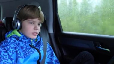 Aile gezisi. Aile karayolu üzerinde kullanıyor. Teen arabada oturan ve kulaklık üzerinden müzik