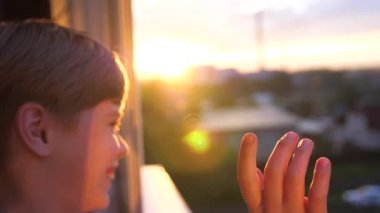 Genç sabah pencerenin yanında duran adam. Güneşin ilk ışınları oda aydınlatmak. Adam elini dalgalar, gün başına ağırlıyor