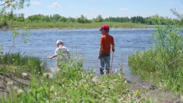 Dos niños pescan en la orilla del río. Hermoso paisaje de verano. recreación al aire libre . — Vídeo de stock