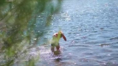 Mutlu erkek dağ nehirde yüzüyor. Sprey, sıcak yaz günü su
